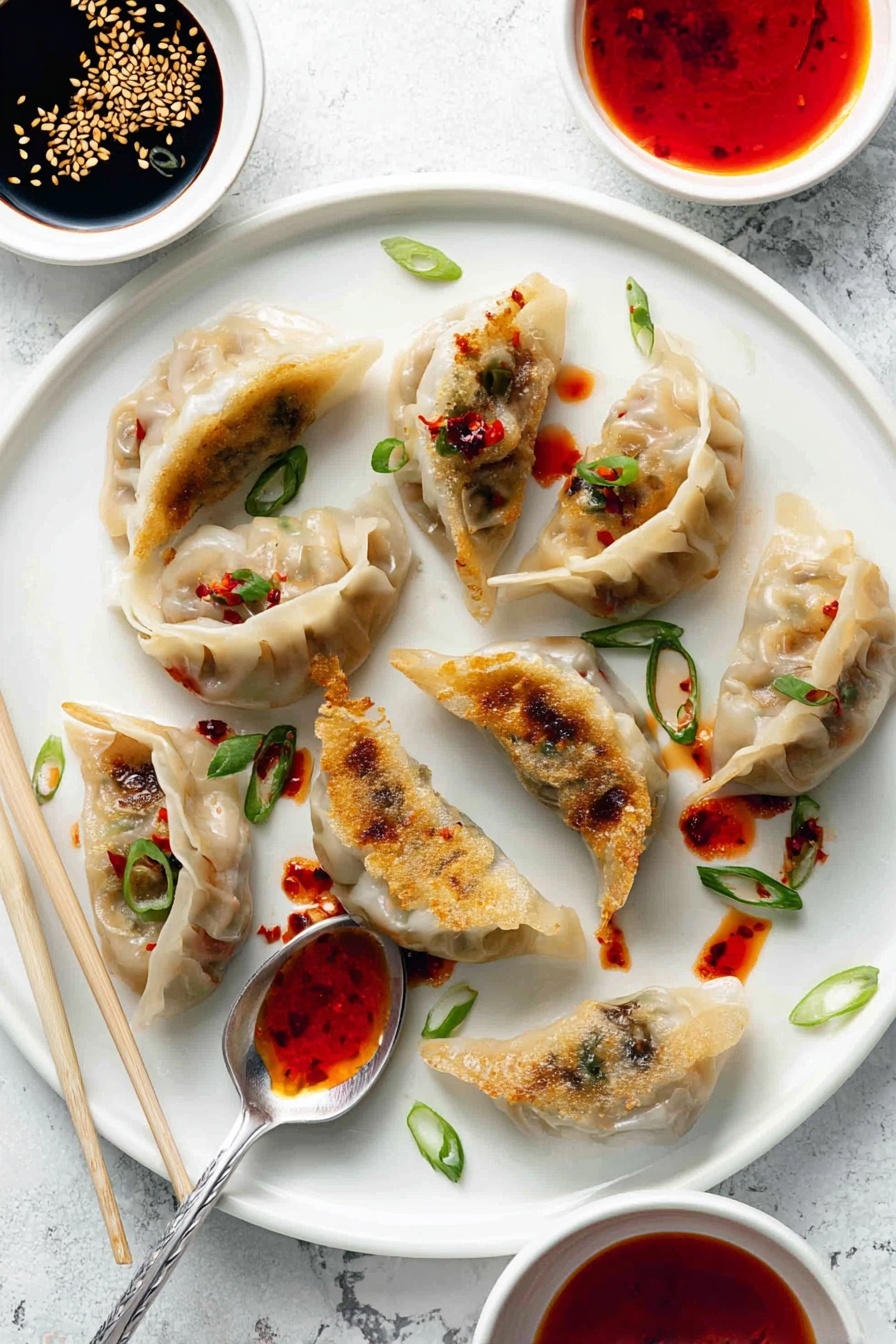 The image shows a white plate with eleven dumplings arranged in a casual pattern. The dumplings have a light beige, slightly translucent wrapper that shows bits of their filling inside. Some of the dumplings have golden brown pan-fried sides which add a crispy texture contrast. Small drops of bright red chili oil are scattered around and on some dumplings, adding vivid pops of color. Thin slices of green onion are sprinkled over the dumplings and plate, giving fresh green highlights. Above the plate, there are two small white bowls, one filled with dark soy sauce topped with sesame seeds, and the other with bright red chili sauce. A shiny spoon lies on the plate with red chili sauce on it. The background surface has a white marbled texture. photo taken with an iphone --ar 2:3 --v 7